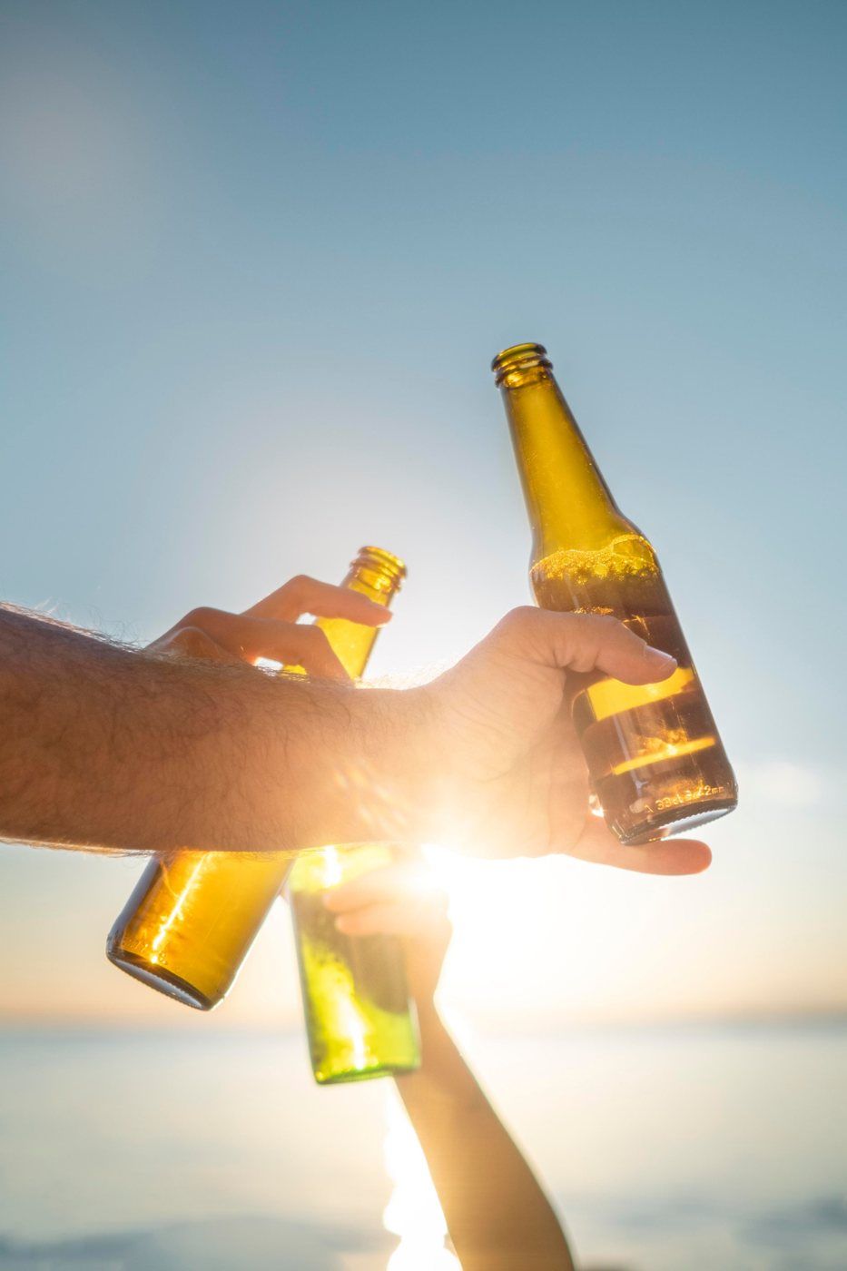 Brindis con cervezas frente al mar al atardecer